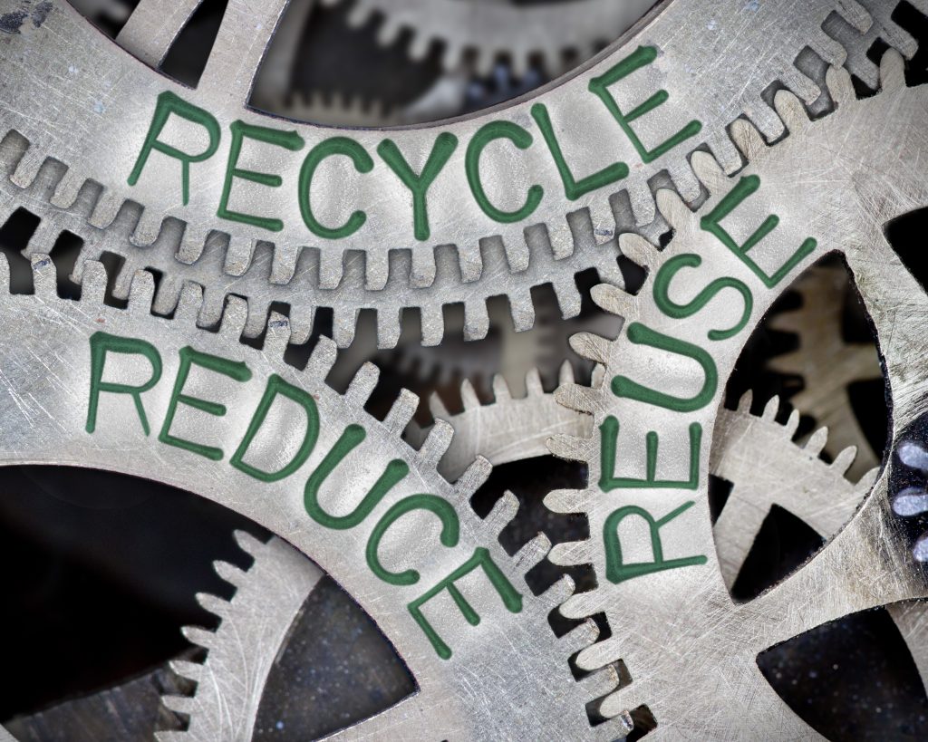 Tooth wheel mechanism with RECYCLE, REUSE, REDUCE words imprinted on metal surface
