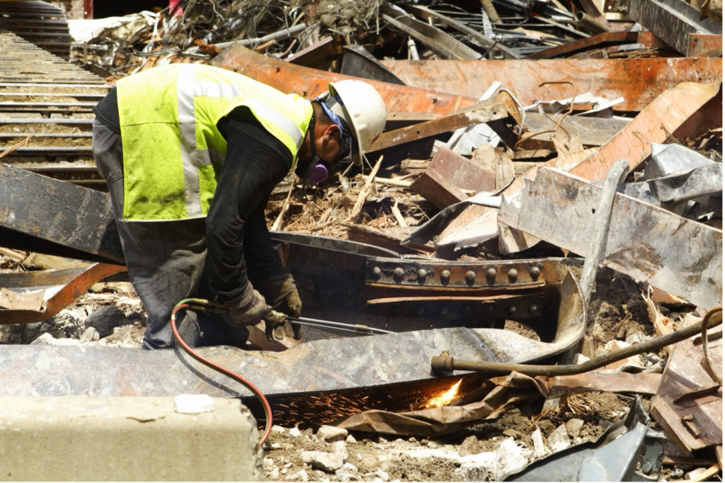 A worker cutting sheet metal in a scrap yard